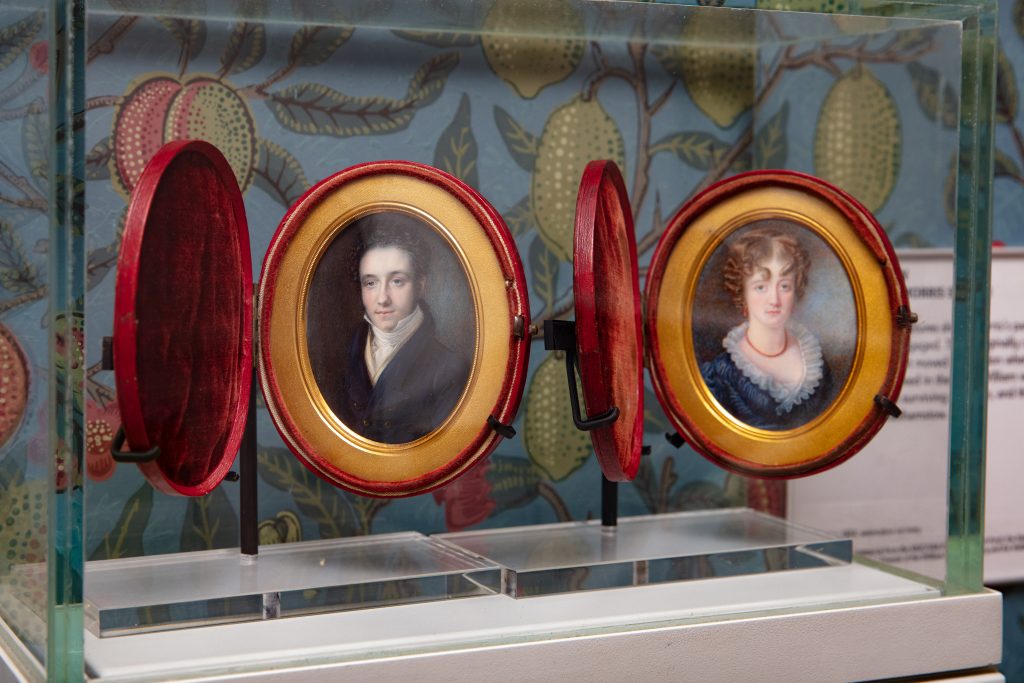 Image of miniature portraits of the Morris family, enclosed within a display case within the Gallery. The portraits are contained in red and gold cases.