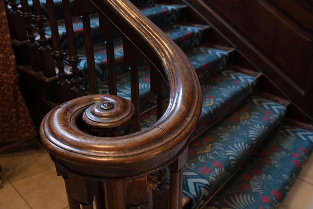 A close up image of a wooden swirling bannister at the bottom of a staircase