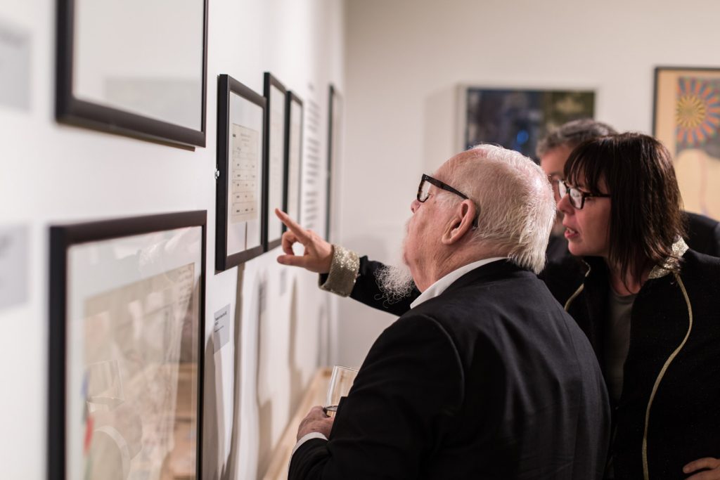 Visitors look at artwork displayed on a wall