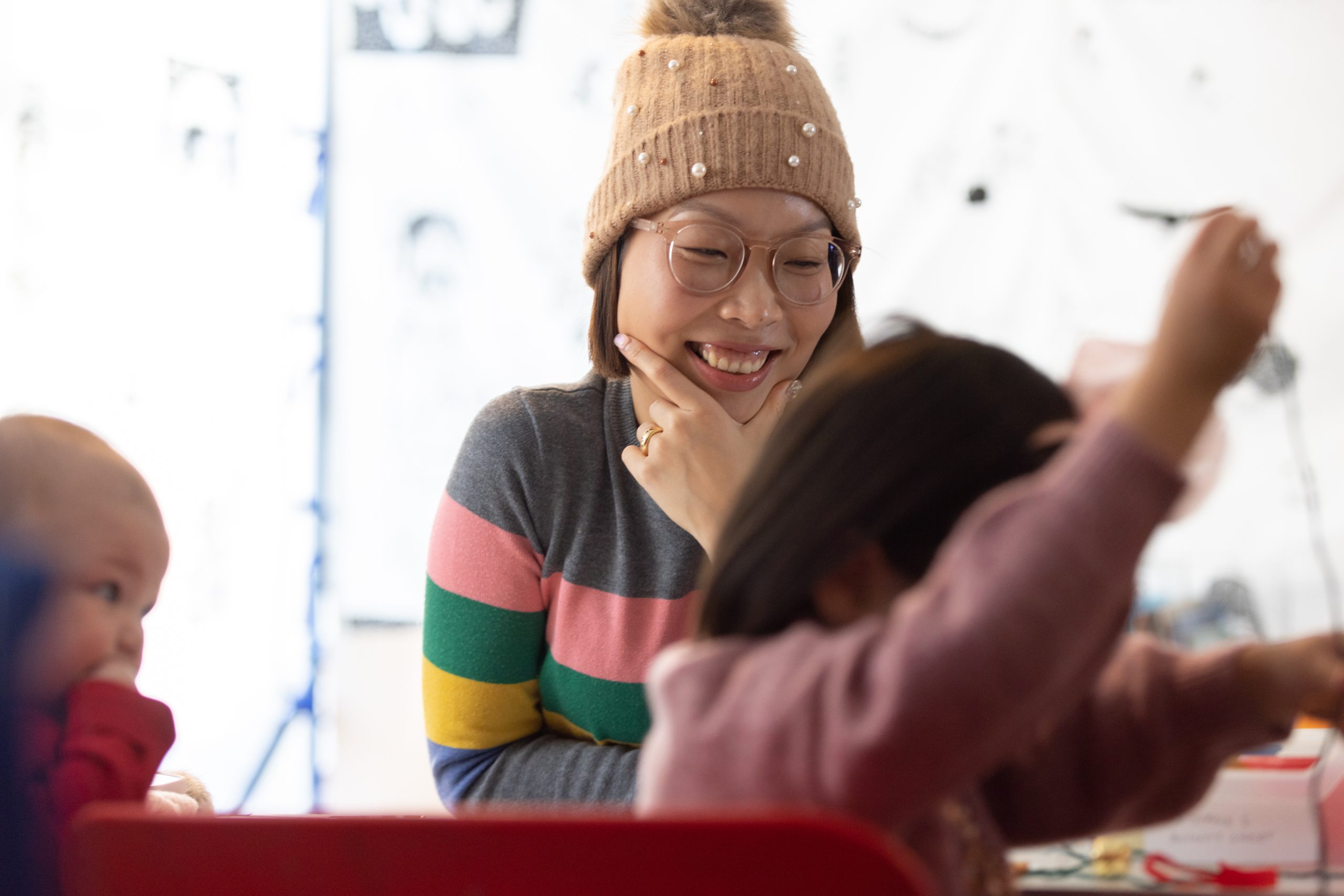 A mother smiles as her children enjoy craft activities.