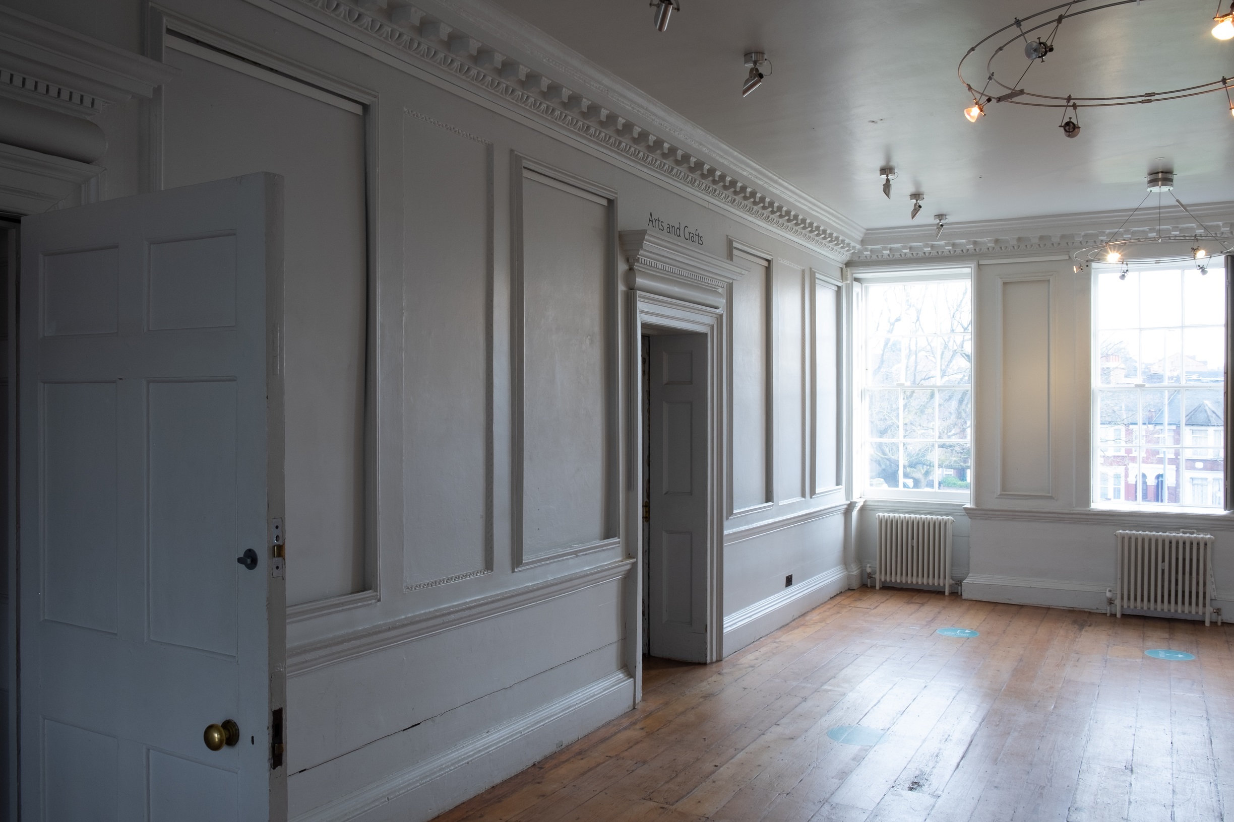 Upstairs landing space or Story Lounge at William Morris Gallery. Panelled white walls with wood floors.