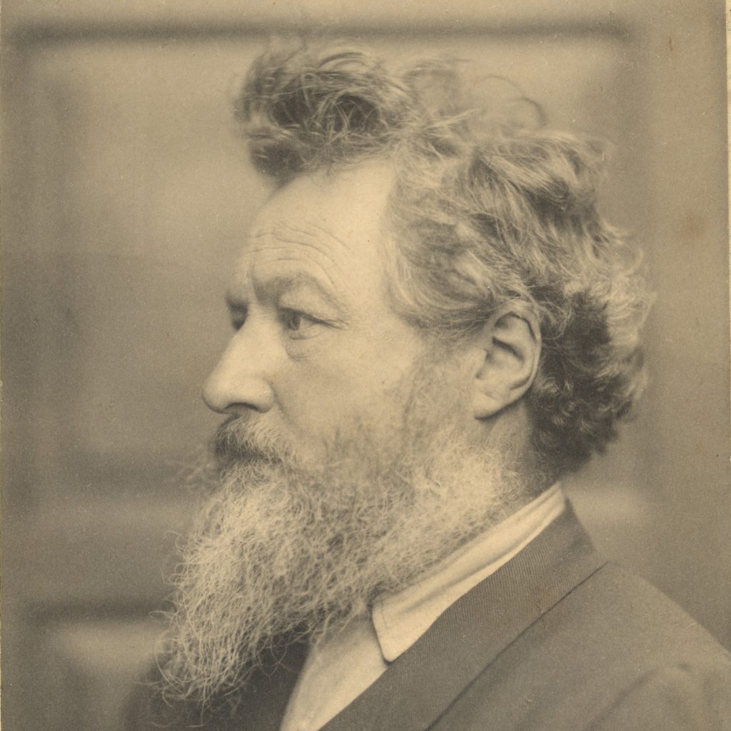 A black and white photograph portrait of William Morris. The image is taken in profile.