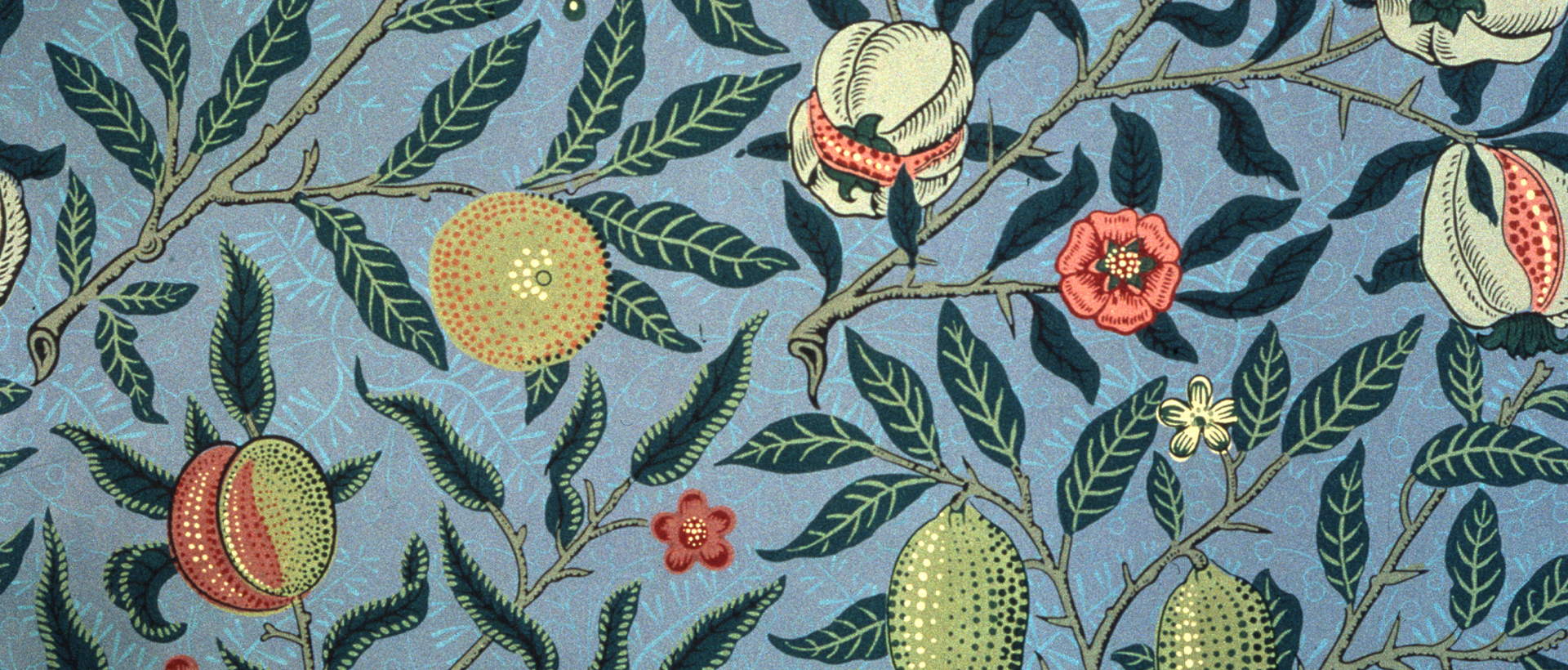 Wallpaper designed by William Morris in 1862. The pattern features pomegranates, oranges and lemons surrounded by leaves and flowers against a blue background.