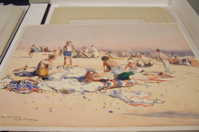 Busy beach scene with figures in swimwear relaxing on towels