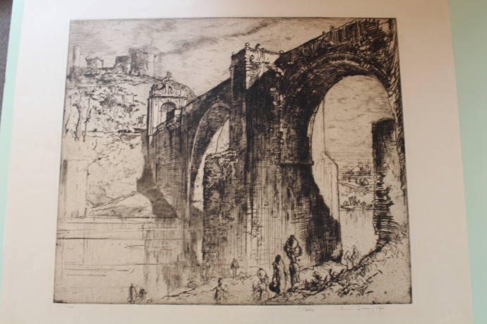 Image of a fortified arched bridge with gateway on far bank and town behind, women carrying water pots down to the river foreground