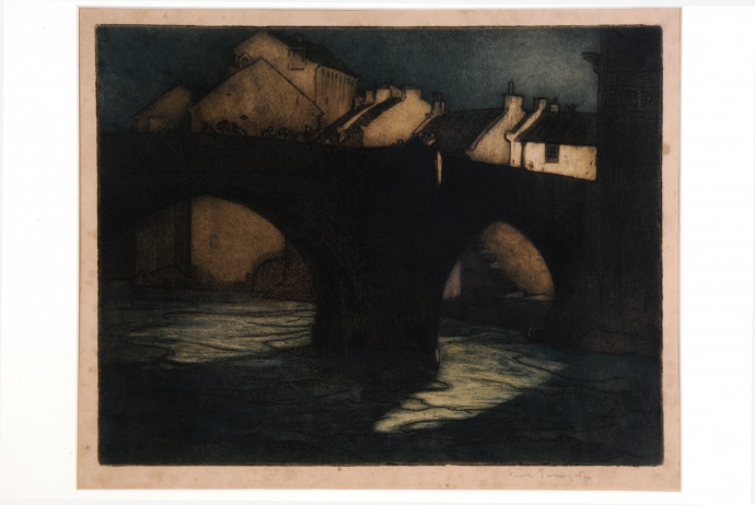 Dark bridge over river with cottages beyond