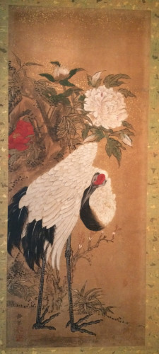 Crane standing with large red and white flowers above