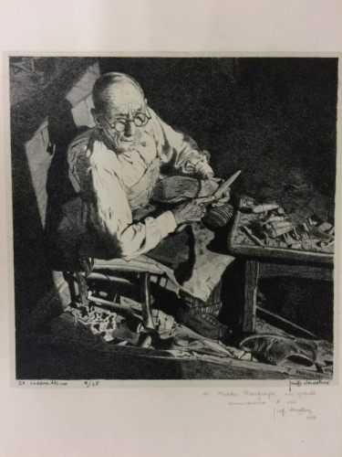 man sits at table, working with tools, looking up at the viewer above