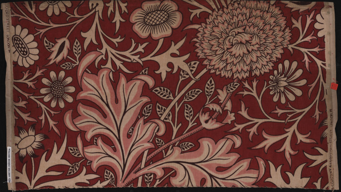 A floral pattern of curling leaves and ruffled flower heads against a deep red background
