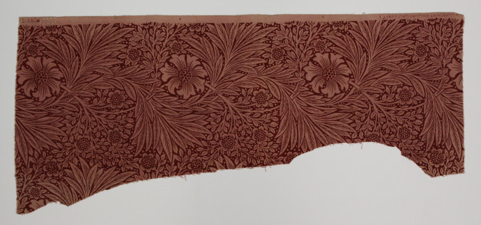 Textile sample with curved sections cut from the fabric. Features a floral design in shades of red.