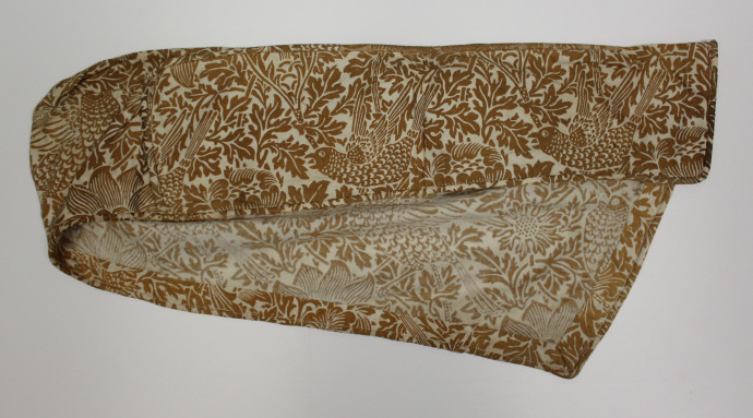 Sample of fabric made up to look like a cover for the arm of a chair. Features a floral design with rows of birds.