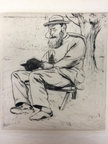man with hat and glasses seated outside reading