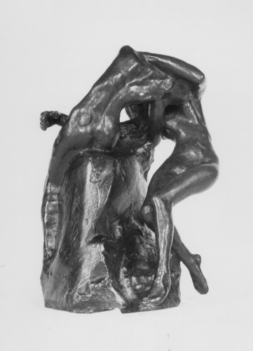 Two nude female figures in bronze, one seated on a rock entwined in an embrace with the other who stands on bent legs. Front view.