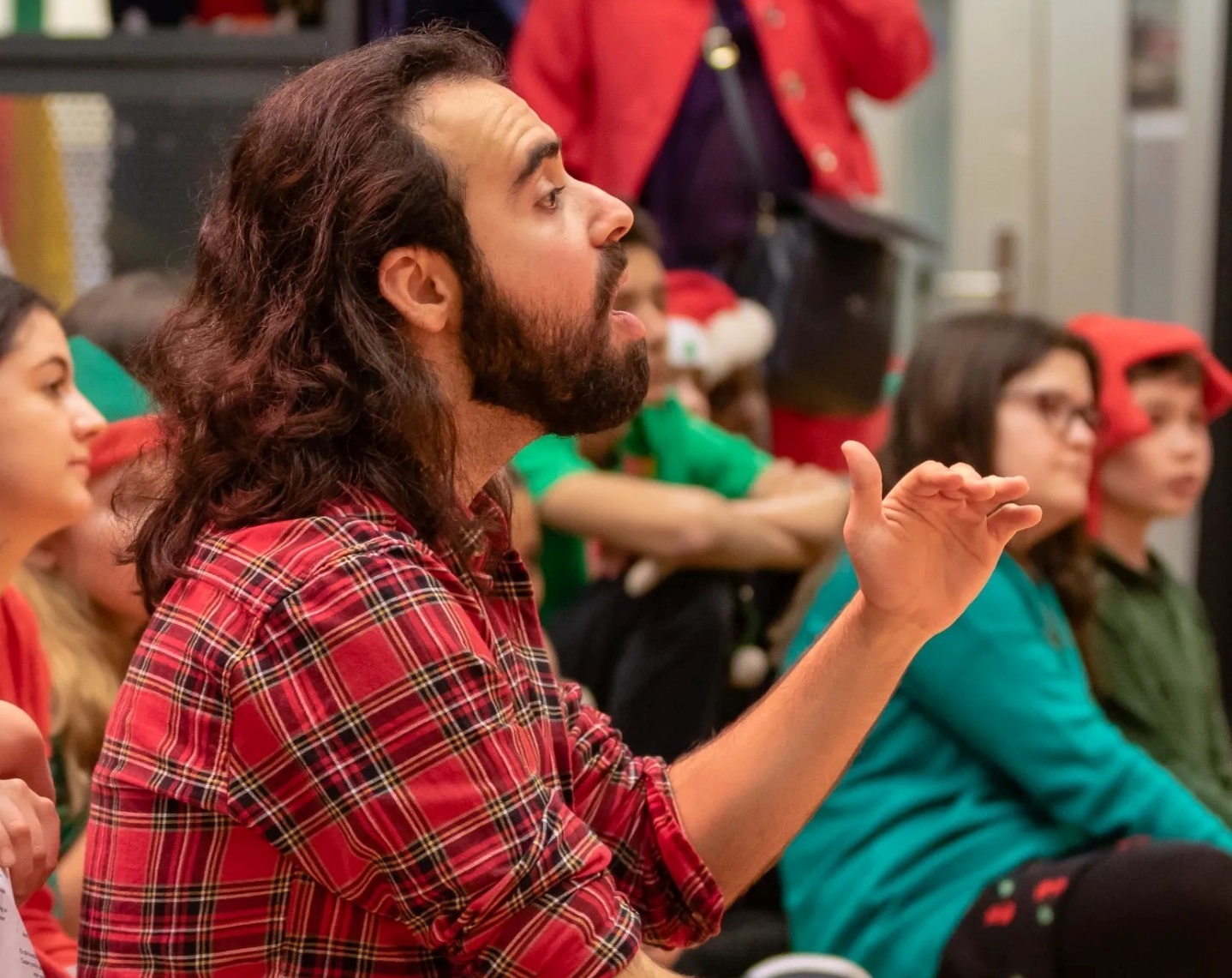 Storyteller speaking. Sitting with a group on the floor.