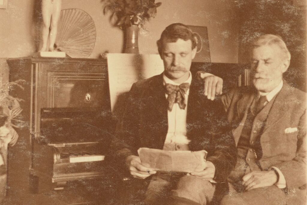 Sepia photograph of two men reading. Turn of the 20th century.